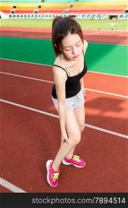 Asian woman jogger holding hurt leg on track