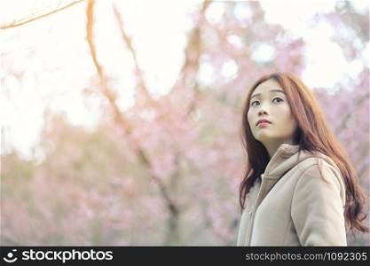 Asian Woman look with cherry blossom nature background