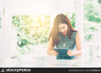 Asian woman looking tablet have a angry and upset outside in the park - expression and stress of communication concept.