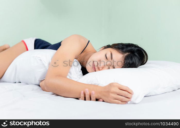 Asian woman lying and sleep on the bed hugging bolster.