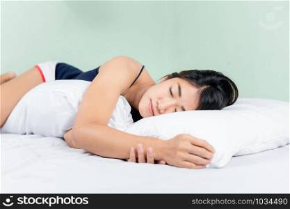 Asian woman lying and sleep on the bed hugging bolster.