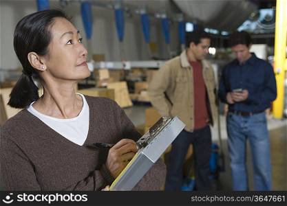 Asian woman making notes in distribution warehouse