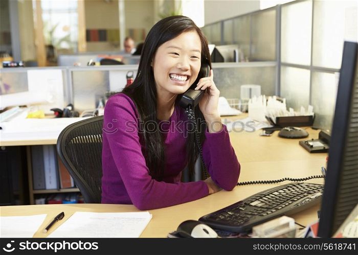 Asian Woman On Phone In Busy Modern Office