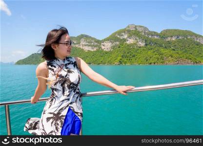 Asian woman on the boat. Asian young woman with eyeglasses smiling happily on the boat while cruising the beautiful natural of the blue sea and sky in summer at Mu Ko Ang Thong National Park, Surat Thani, Thailand