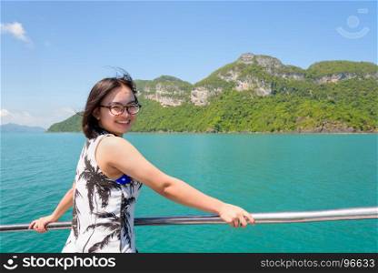 Asian woman on the boat. Asian young woman with eyeglasses smiling happily on the boat while cruising the beautiful natural of the blue sea and sky in summer at Mu Ko Ang Thong National Park, Surat Thani, Thailand