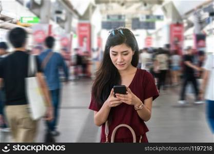 Asian woman passenger with casual suit using the smart mobile phone in the BTS Skytrain rails or MRT subway for travel in the big city, lifestyle and transportation concept