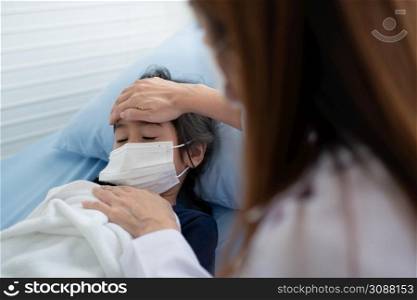 Asian woman pediatrician doctor put hand on chest for exam a little girl patient and heck heart lungs of kid, Good family doctor visiting child at home, Healthcare and medicine for childhood concept.