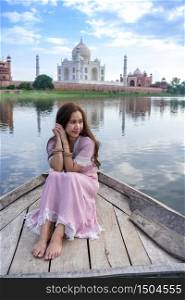 Asian woman posing over Taj Mahal from a boat, Agra, India