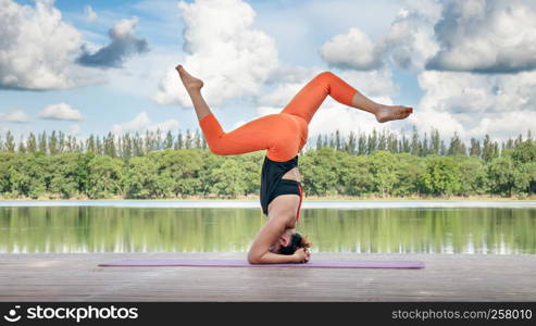 Asian woman practicing yoga pose , exercise outdoors with view of beautiful lake - relax in nature. Asian woman practicing yoga pose