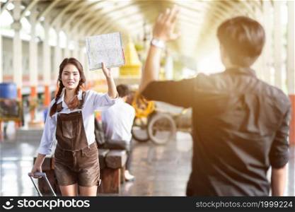 Asian woman pregnant Hold map say goodbye With a young man in at railway station travel,traveler with backpack in summer Holiday concept Thailand