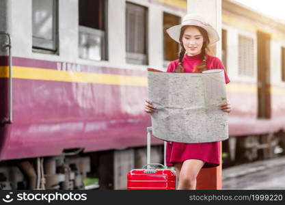 Asian woman pregnant in red dress carrying red luggage and look at the map at railway station travel,traveler with backpack in summer Holiday concept Thailand