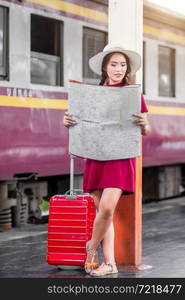 Asian woman pregnant in red dress carrying red luggage and look at the map at railway station travel,traveler with backpack in summer Holiday concept Thailand