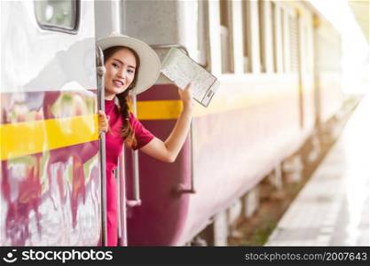 Asian woman pregnant in red dress holding a map and hand up say hello on the train.travel railway station travel.