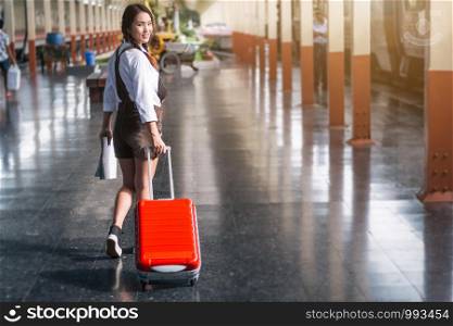 Asian woman pregnant travel carrying her trolley red bag and map in railway station travel.