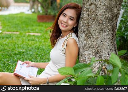 Asian woman reading a book in the garden for relaxation