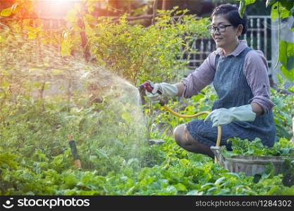 asian woman relaxing and watering in home garden
