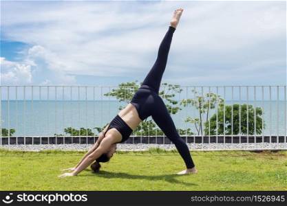 Asian woman relaxing in yoga Seperate leg stretching Pose exercises muscle for warm up on the beach in with seaside,Feeling so comfortable and relax in holiday