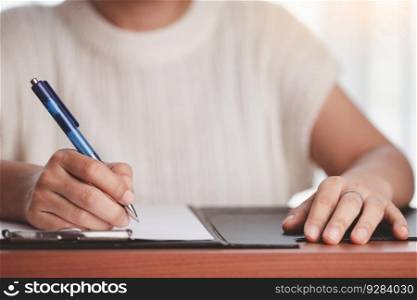 Asian woman&rsquo;s hand holding a pen and writing something on the notebook for the concept of work and study.