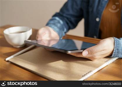 Asian woman's hands are using tablet on wooden table