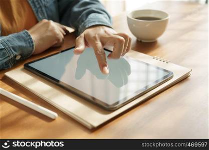 Asian woman's hands are using tablet on wooden table