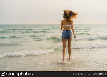 Asian woman running on sand beach. Young happy female in bikini relax and fun run near tropical sea when sunset while holiday, vacation, summer trip concept.