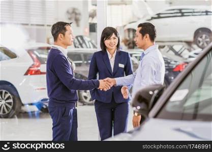 Asian woman sales representative introducing the service to customer, Mechanic leader handshake with the customer in maintenance service center which is a part of showroom, business and customer care