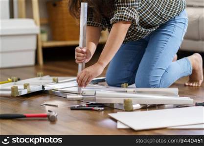 Asian Woman self repairs furniture renovation using equipment to diy repairing furniture sitting on the floor at home.