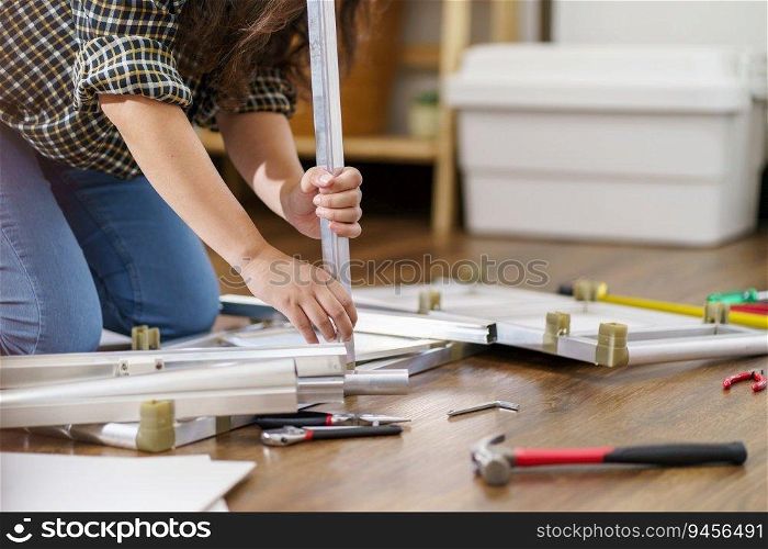 Asian Woman self repairs furniture renovation using equipment to diy repairing furniture sitting on the floor at home.