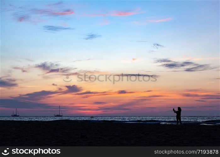 Asian woman selfie with smartphone on the beach while beautiful sky after sunset