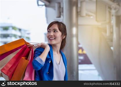 asian woman shopping smile and holding shopping bag with shopping mall background, consumerism, sale and people online concept