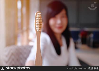 Asian woman showing wooden bamboo toothbrush, sustainable lifestyle, zero waste concept