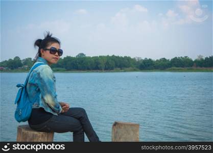 Asian woman sit at stump on riverside, Yasothorn Thailand Asia
