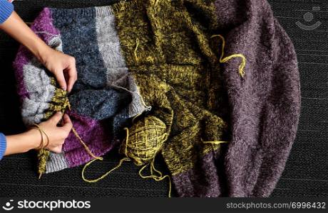 Asian woman sit on floor of home to knit woolen blanket for warm in wintertime, knitting is hobby in leisure activity to make handmade gift, photo of woman hand working from top view on day