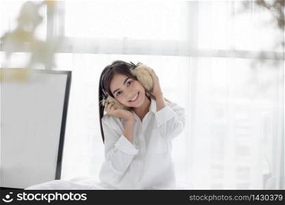 Asian woman Smile feel carefree and she lying on the bed in the morning after waking up and young beautiful girl will listening to music on headphones