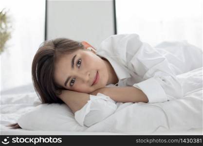 Asian woman Smile feel carefree and she lying on the bed in the morning after waking up and young beautiful girl will listening to music on headphones