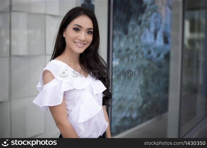 Asian Woman smiling and happy with perfect smile and white teeth in a shopping mall and looking at camera
