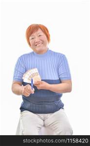 Asian woman smiling with 50 euro banknotes in one hand and with the other pointing them with a pen, isolated on white background. Commercial exchange concept.