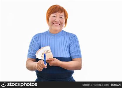 Asian woman smiling with 50 euro banknotes in one hand and with the other pointing them with a pen, isolated on white background. Commercial exchange concept.