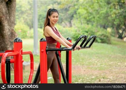 Asian woman stand and exercise with equipment in park or garden also look at camera and smile.