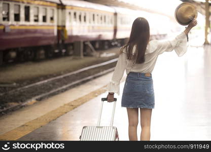 Asian woman standing back Carrying luggage At the railway station platform