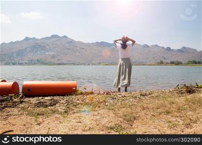 Asian woman standing near the river with mountain view on background. Happy travel and lifestyle concept