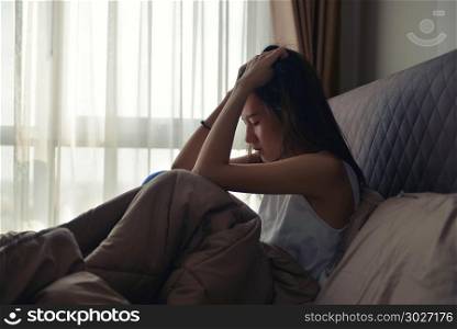 Asian Woman Suffering From Depression Sitting On Bed