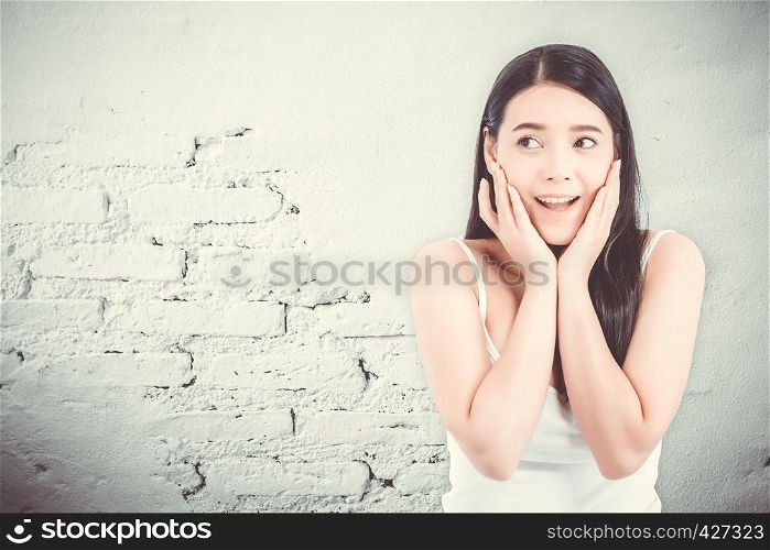 Asian woman surprise hold cheek with hand, Beautiful girl with presenting your product with expression excited and surprise on cement background, Expressive facial emotion concept.
