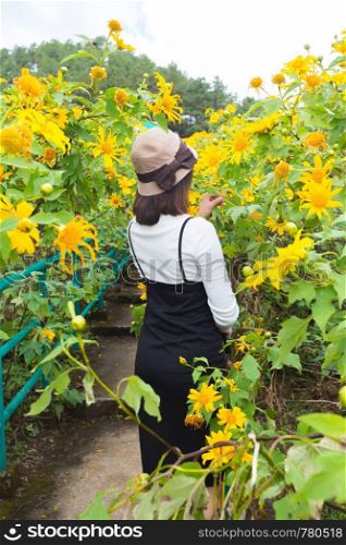 Asian woman traveler in holiday. Relax and happy in yellow flower field.