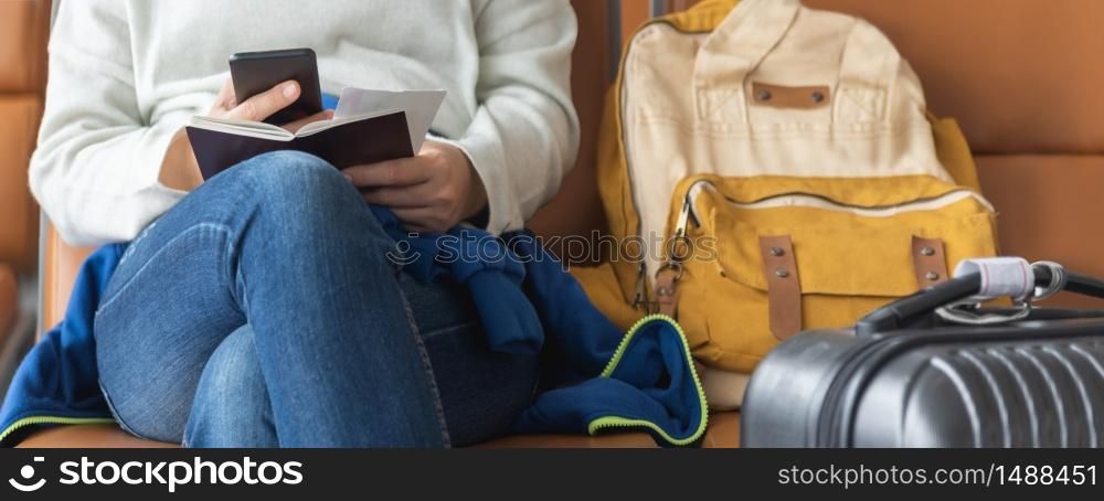 Asian woman traveler is sitting and using smartphone while waiting for the flight at the airport. Holiday and Vacation. Banner, Panoramic view.