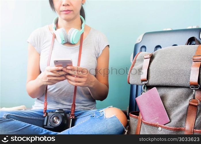Asian woman traveler with headphones and camera using smart phon. Asian woman traveler with headphones and camera using smart phone, luggage suitcase and backpack by her side, Travel vacation concept
