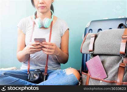 Asian woman traveler with headphones and camera using smart phon. Asian woman traveler with headphones and camera using smart phone, luggage suitcase and backpack by her side, Travel vacation concept