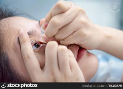 Asian woman use eye drop or artificial tears by drops in to the eye for inflammation or dryness problem therapy of eyeball for eyes health. Woman use eye drop, artificial tears to the eye