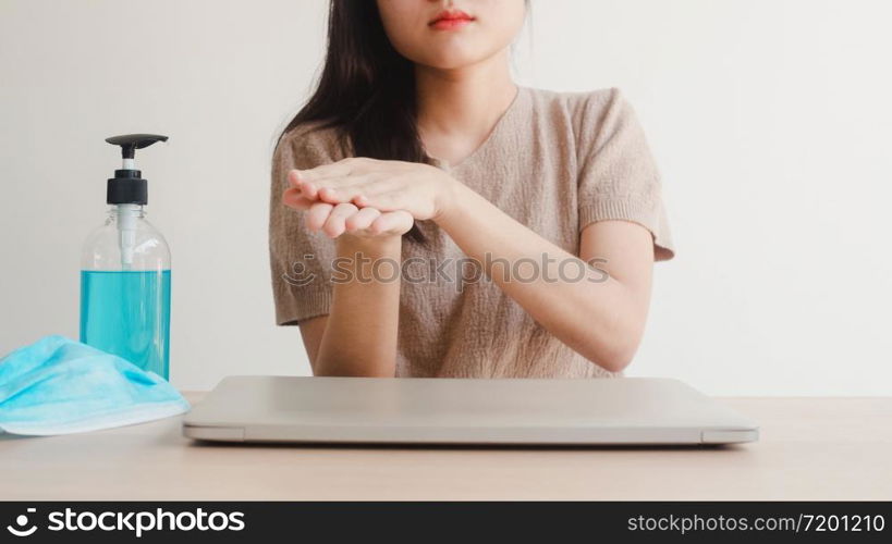 Asian woman using alcohol gel hand sanitizer wash hand before open laptop for protect coronavirus. Female push alcohol to clean for hygiene when social distancing stay at home and self quarantine time