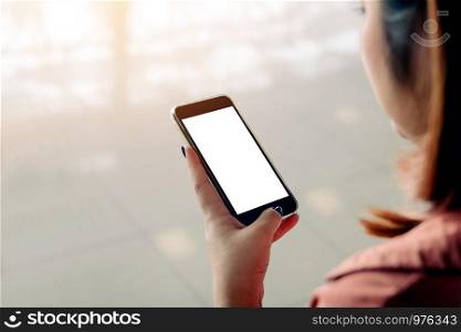 Asian woman using and touching a blank white screen smartphone in airport terminal.